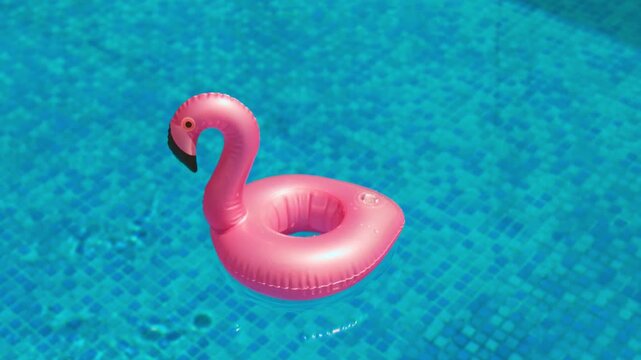 Pink Flamingo Inflatable Pool Float Drifting on Clear Blue Swimming Pool Water During Summer Vacation