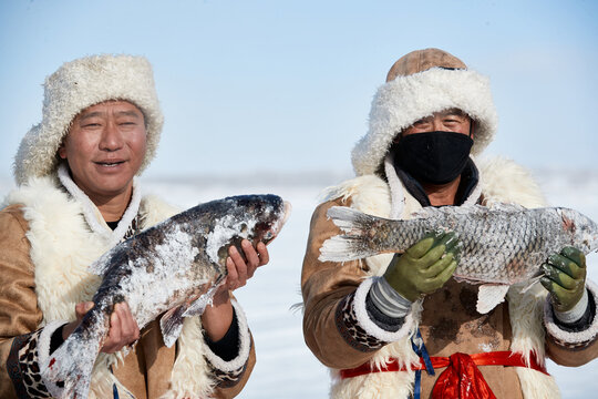 People ice-fishing on the frozen lake during the cold winter.