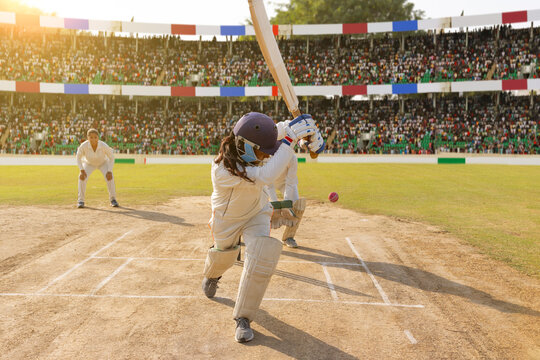 Cricketer hitting a ball in a packed stadium