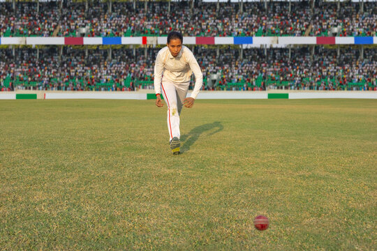 Female cricketer chasing a ball on the field