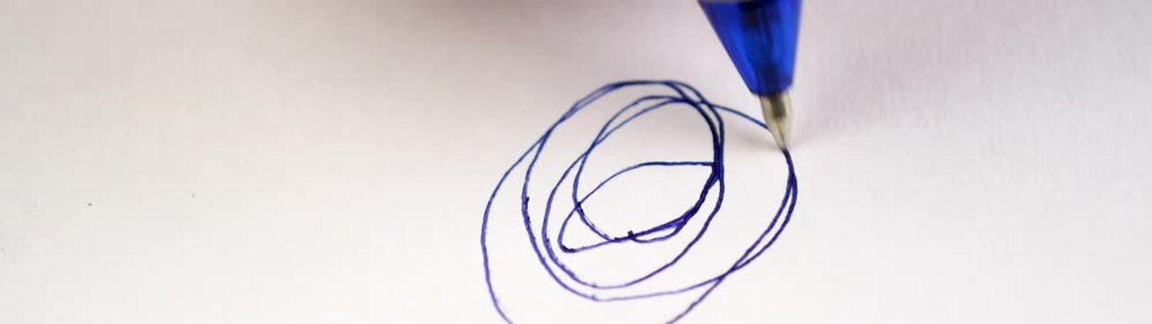 Pen is creating a spiral doodle on white paper symbolizing creative process ideas and thinking.