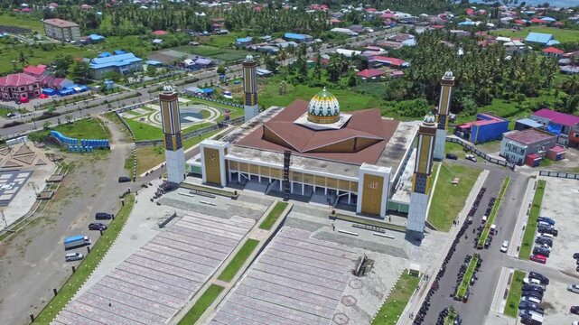 An aerial shot of a magnificent mosque Masjid Raya Shaful Khairaat Sofifi Tidore with mountains and the sea. Ideal for projects on religion, travel, and culture