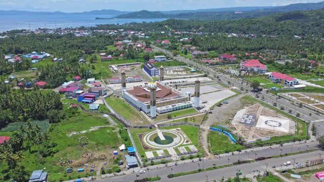 An aerial shot of a magnificent mosque Masjid Raya Shaful Khairaat Sofifi Tidore with mountains and the sea. Ideal for projects on religion, travel, and culture
