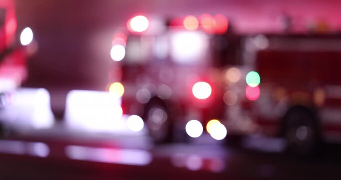 Abstracted de-focused bokeh view of fire engine emergency assets arriving on scene at night.