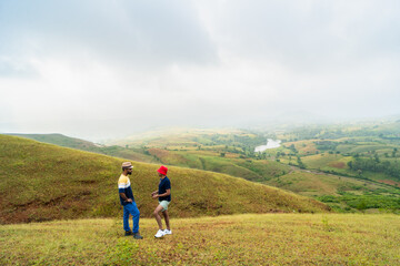 Naklejka premium Two friends standing on a grassy hill overlooking a misty valley in Banswara, Udaipur, Rajasthan