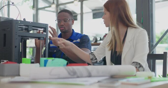 Engineers examining 3D printed prototype from recycled material at desktop printer in eco workshop