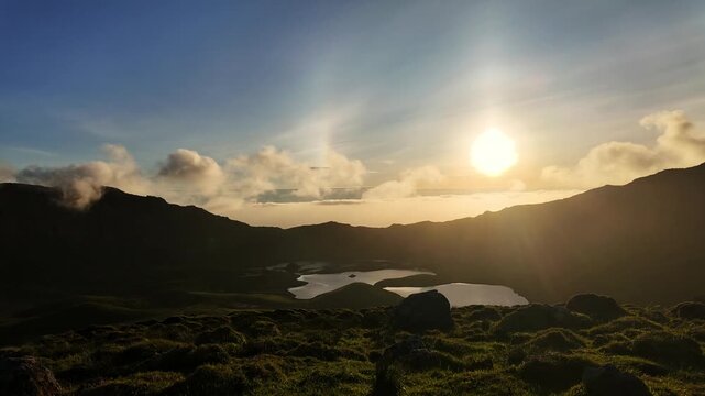 Sunset clouds drift over volcanic caldera lake and rugged hills in remote Azores landscape