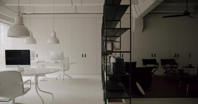 Minimalist office interior with a striking black and white design contrast, featuring modern furniture, computers, and a stark division between light and dark creative workspaces