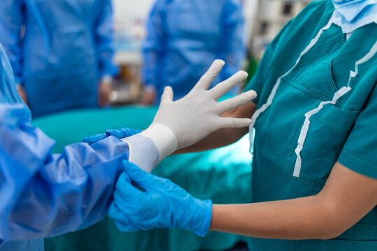 Sterile surgical nurse assists a surgeon in putting on sterile gloves in a modern hospital operating room, ensuring strict hygiene protocols are followed before a medical procedure begins. 