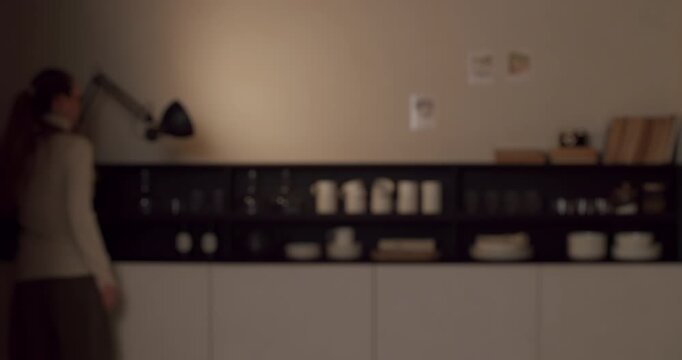 Carefree woman with a long ponytail enjoying herself and dancing happily in the kitchen of her cozy apartment, listening to music and celebrating her freedom and simple joyful moments at home