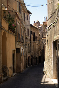Vicolo antico di un borgo europeo con edifici in pietra, facciate vissute e dettagli architettonici tradizionali, illuminato dalla luce naturale che esalta l&rsquo;atmosfera pittoresca e senza tempo del luo