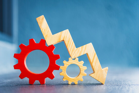 Wooden downward arrow graph on red and yellow gears. Concept of economic recession, business crisis, financial loss, system failure, inflation impact and industrial market decrease.