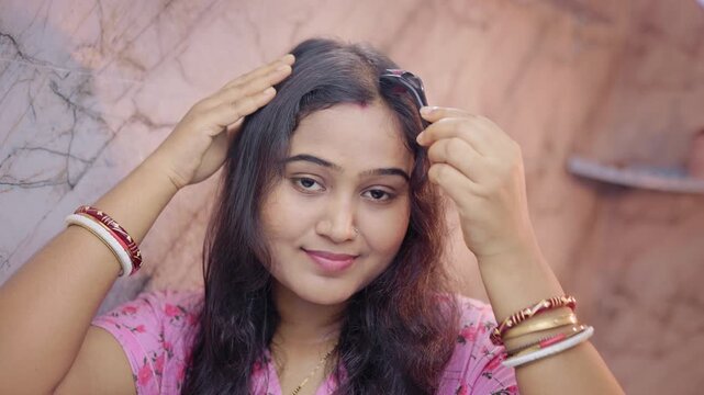 Indian woman using derma roller on thinning scalp area in the modern bathroom, microneedling treatment for hair loss.