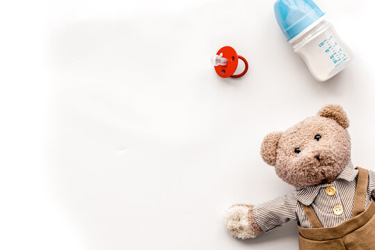 Feed baby concept. Teddy bear toy near small bottle with food on white background top view copy space