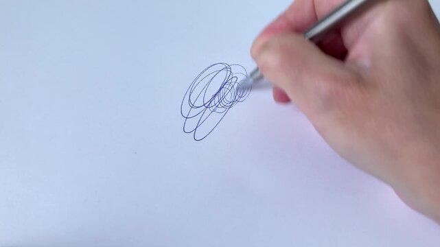 A woman draws nervous patterns on a blank sheet, a fancy ornament on a white background. Close-up of a woman's hand with a pen. Anxiety coming out through the pen, stress, depression