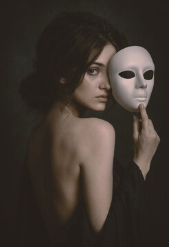 Mysterious Beautiful Woman Holding White Mask to Her Face - Conceptual Portrait of Dual Identity and Alter Ego