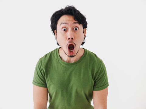 Surprised and shocked face Asian man in green t-shirt isolated on white.
