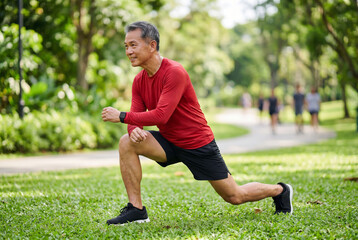 Naklejka premium Active senior asian man doing lunges outdoors in a green park for fitness and healthy living