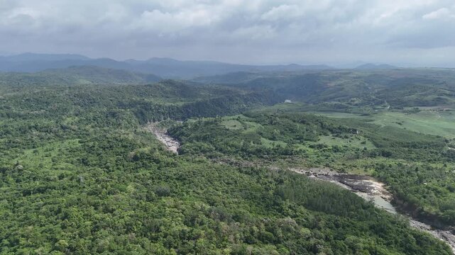 Drone footage captured over Ea So National Park in Dak Lak, Vietnam, during the dry season in May. The drone flies forward above dry forest landscapes, revealing a winding river with relatively low wa