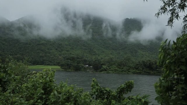 Misty Brahmaputra River Flowing Through Lush Green Hills During Light Rain in Assam, India.