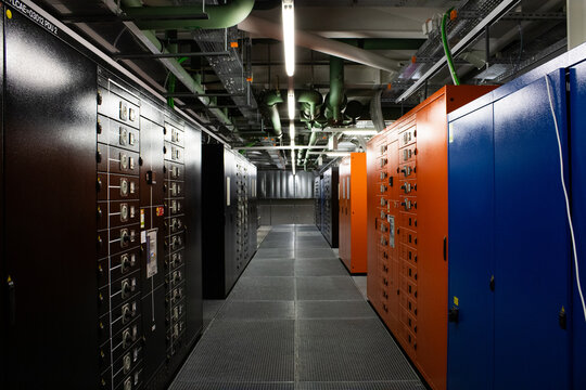 Lugano, Ticino, Switzerland - 18 March 2026: View of the Swiss National Supercomputing Centre with rows of industrial electrical cabinets, server infrastructure, and overhead piping.