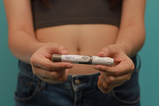 GLP 1 injection pen held by woman for medical weight management, focus on hands and device, healthy lifestyle concept