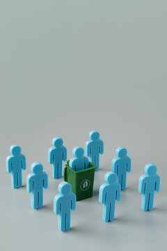 A blue figure in a green trash bin among a group on a grey background. Corporate layoffs, downsizing, employee termination, rejection concept. Copy space for text.