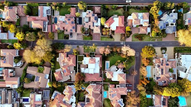 Top-down aerial descending view over luxury residential suburb neighborhood. Captures clean streets, symmetrical housing architecture, swimming pools, and manicured green lawns.