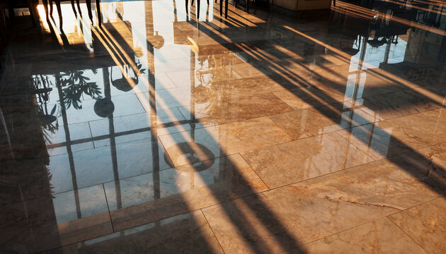 Long, dramatic shadows stretch across a highly polished, light-colored marble floor, reflecting interior elements and bright sunlight streaming through windows.