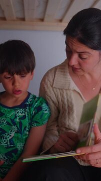 Mother coaching child through reading practice during evening routine, highlighting academic development, parental engagement, curiosity and meaningful family interaction