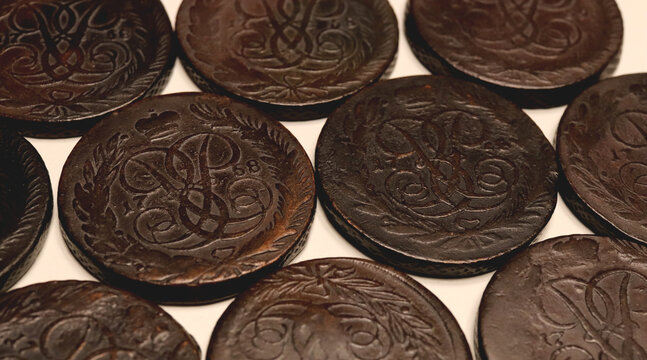 Close-up of old dark brown 5 kopeck coins Elizabeth Petrovna 1758-1762 spread on a light background, showing worn engraved details and antique texture. Ideal for history, money, collecting.