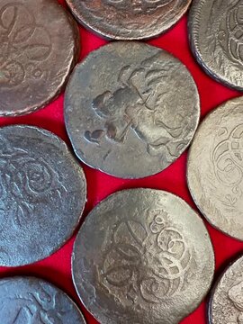 Close-up of old worn 1 kopeck coins 1757-1761 Russian Empire Elizabeth I on bright red fabric, showing aged metal surfaces, faded engravings and antique money details for history.