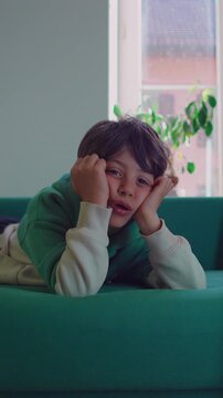 Young child immersed in digital content while resting on couch, highlighting screen engagement, focused attention, entertainment and contemporary family life
