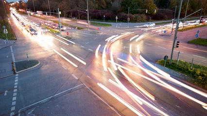 Autos fahren in der Dämmerung mit Licht über die Kreuzung einer vierspurige Straße © Wolfilser