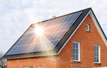 Fototapeta premium Eine Photovoltaikanlage auf dem Hausdach von einem Neubau erzeugt grünen Strom - FOTOMONTAGE