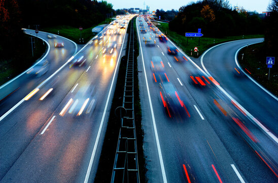 Autos fahren in der D&auml;mmerung mit Licht &uuml;ber eine vierspurige Stra&szlig;e