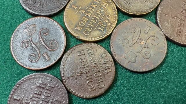 Close-up of old Russian Empire copper 1/4 quarter kopeck coins 1839-1848 Nicholas I on green felt, showing worn details, dates and lettering. Antique money background for history, collecting.