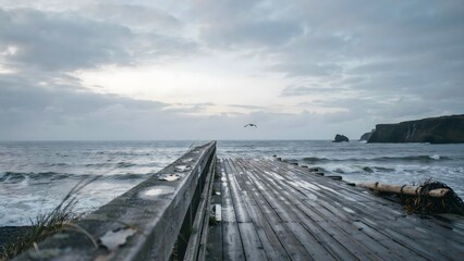 Fototapeta premium Wooden Pier Extending into Ocean Under Cloudy Sky with Cliffs in the Distance