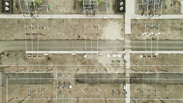 High voltage electrical substation with transformers and power lines seen from an aerial top down perspective, highlighting the complex grid infrastructure for energy distribution and generation