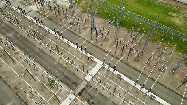 Aerial top down view of a large scale electrical substation showcasing the intricate network of high voltage power lines, transformers, and insulators crucial for power distribution and generation