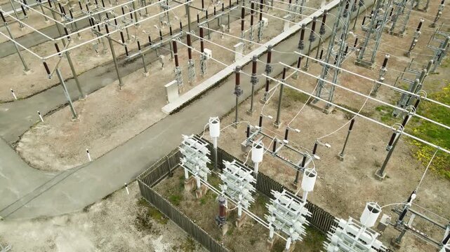 High voltage electrical substation with tall pylons and hog voltage distribution cables. Aerial perspective revealing the complex network of transformers, insulators, and circuit breakers