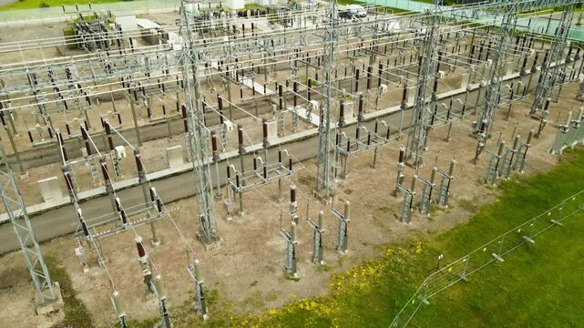 Aerial perspective of a high voltage electrical substation featuring a complex grid of power lines, insulators, and transformers for distributing energy across the electrical network