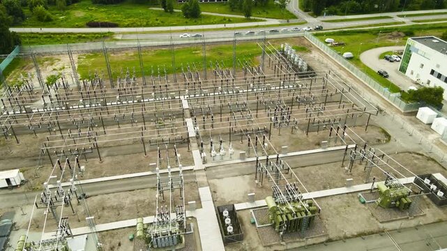 High angle drone footage showing a modern electrical substation with transformers and high voltage power lines, a crucial component of the energy distribution and transmission infrastructure