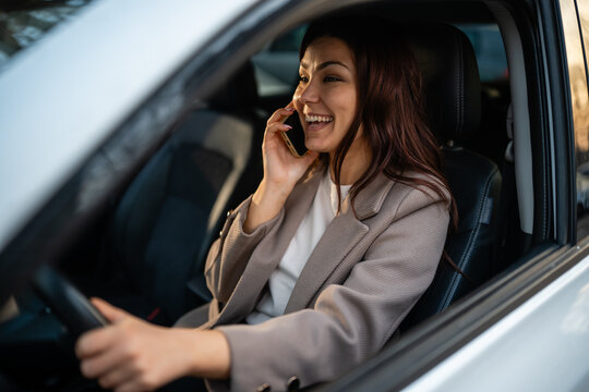 Woman driving car and talking on phone, laughing