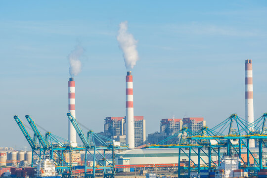 Industrial port and power plant with smokestacks in Shanghai, China. Cargo handling equipment and energy production facilities illustrate logistics, electricity generation, heavy industry