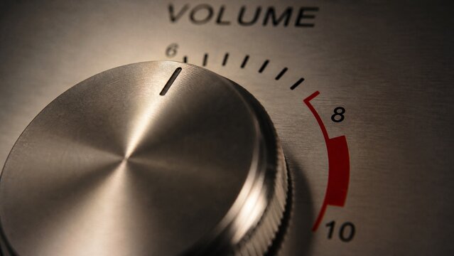 Extreme close-up of a volume knob being turned from low to the maximum red zone.