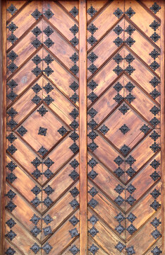 Old wooden gate leaf parts. Ancient wood door with metal rivets. Medieval wooden door with aged iron reinforcements