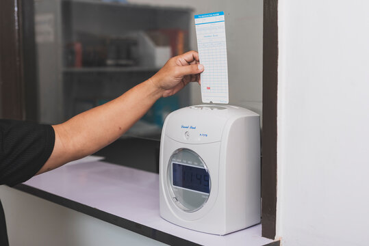 Time clock attendance machine with paper time card in office setting, recording employee work hours for payroll tracking and workforce management.