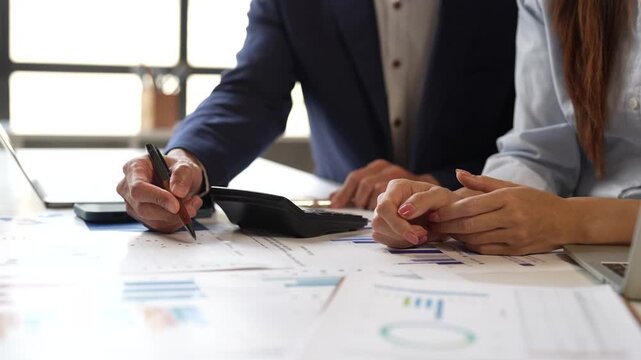 Business colleagues collaborating on a financial report, analyzing marketing data charts, and discussing company investment strategy during a corporate meeting in the office