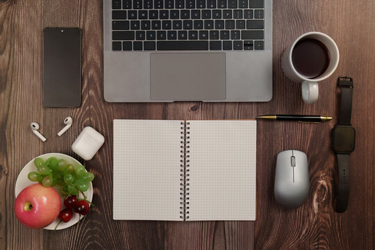 Flat lay of laptop notebook and healthy fruit snack on wooden desk for remote work productivity
